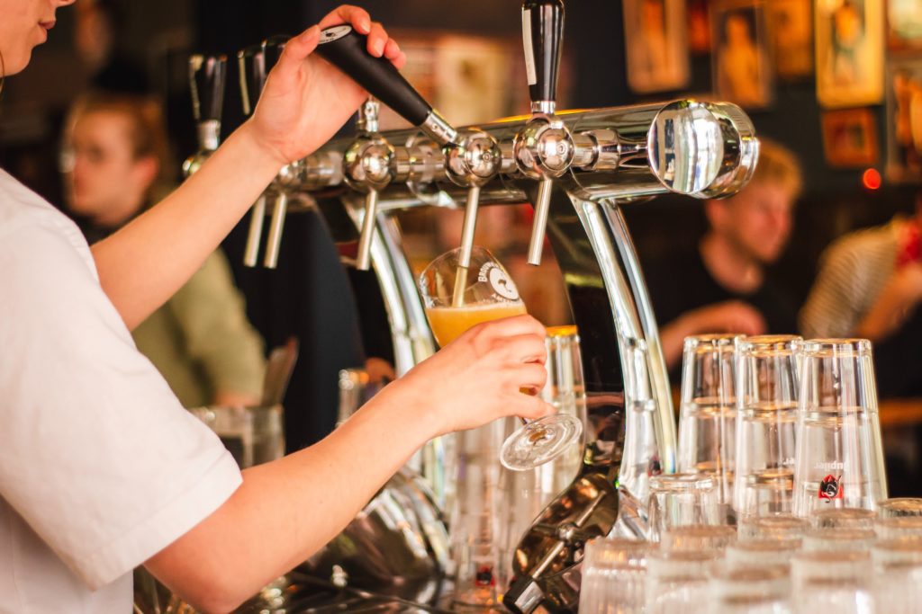 Brewery employee pouring beer on tap