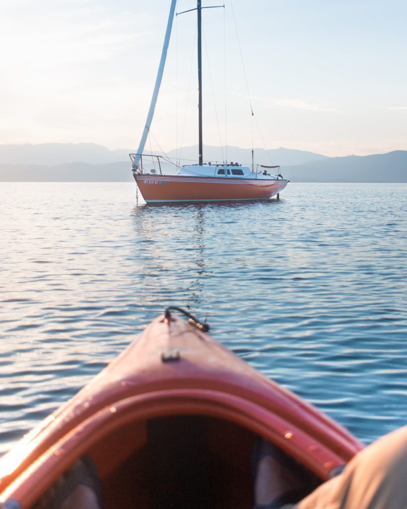  kayaking on a lake alongside a sailboat 